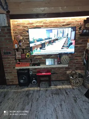 a living room with a large tv on a brick wall at Villa FORESTA in Banja Luka