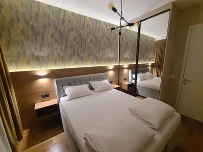 a bedroom with a large white bed and a mirror at GRAND LUX APARTMENTS in Banja Luka