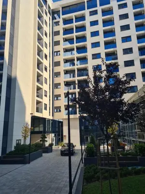 a large white building with a tree in front of it at GRAND LUX APARTMENTS in Banja Luka