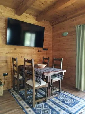 a dining room with a table and chairs and a television at Kuća u šumi - Forest house near National park Una - Air Spa Lohovo in Bihać