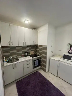 a kitchen with white cabinets and a sink and a microwave at Apartmani BROD in Zenica