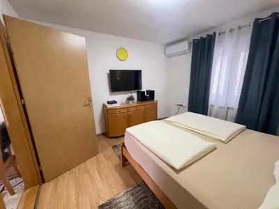 a small bedroom with a bed and a television at Apartmani BROD in Zenica