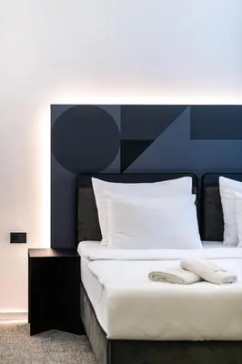 a bed with white sheets and a blue headboard at Hotel Adriale in Kreševo