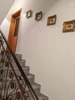 a staircase with a door and pictures on the wall at Apartmani Hrastik 2 in Bihać