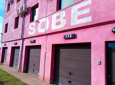 a pink building with three garage doors on it at Motel Gas-Petrol Samac in Bosanski Šamac