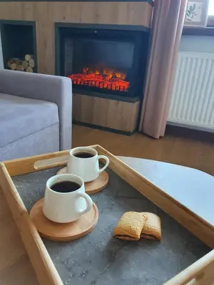 two cups of coffee and bread on a coffee table with a fireplace at Vlašićka ruža Eko FIS 303 in Vlasic