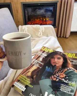 a cup of coffee next to a magazine and a cup of coffee at Vlašićka ruža Eko FIS 303 in Vlasic