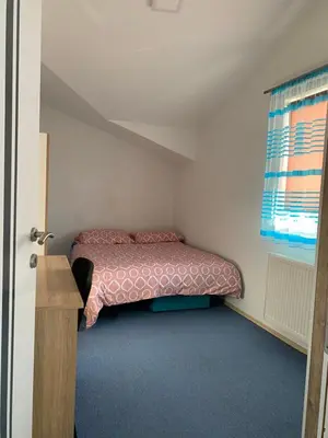 a small bedroom with a bed with pink sheets and a window at Unas apartment in Bihać