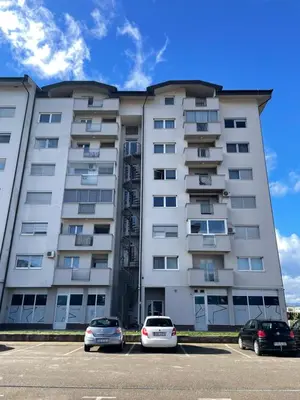 a large white building with cars parked in a parking lot at Unas apartment in Bihać