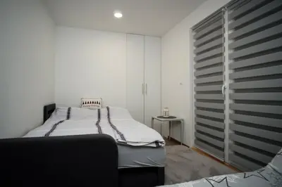 a white bedroom with a bed and a window at Planinska kuca NATURA in Vlasic