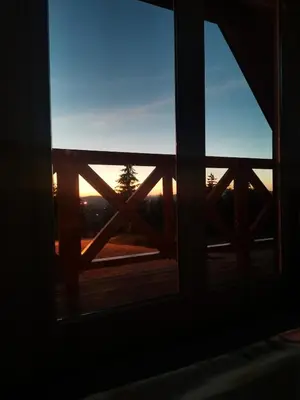 a window with a view of the sunset seen through it at Planinska kuca NATURA in Vlasic