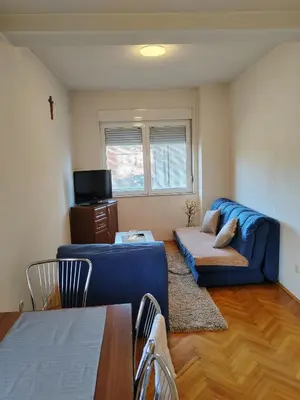 a living room with a blue couch and a table at Apartman Leko in Kupres