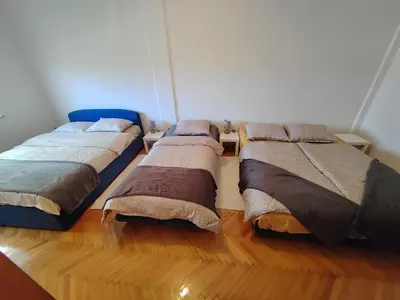 two beds in a room with wooden floors at Apartman Leko in Kupres
