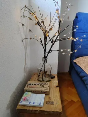 a table with a vase and a tree with lights at Apartman Leko in Kupres