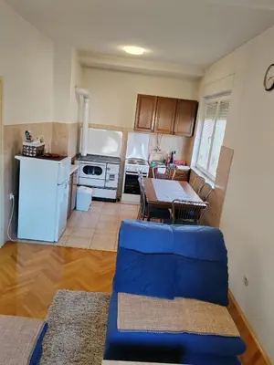 a living room with a table and a kitchen at Apartman Leko in Kupres