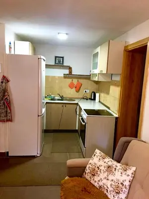 a small kitchen with a white refrigerator and a couch at Vikendica RAJ in Travnik