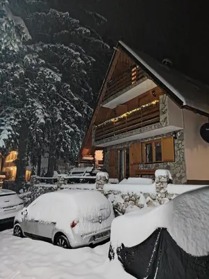 a house with snow covered cars parked in front of it at Vikendica RAJ in Travnik
