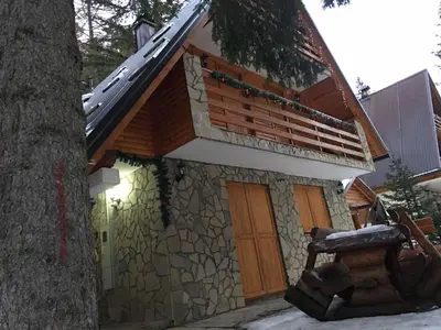 a building with a bench next to a tree at Vikendica RAJ in Travnik