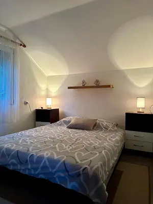 a bed in a bedroom with two lights on the wall at Vikendica Cokori in Banja Luka