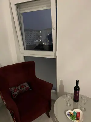 a living room with a chair and a table and a window at 7th Sky in Doboj
