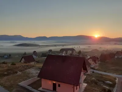 a sunrise over a town with a house and a field at Madonna Sky in Kupres