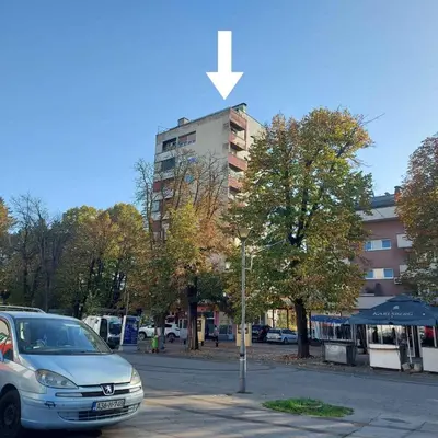 a car parked in a parking lot next to a building at APARTMAN POZORISTE Penthaus in Banja Luka