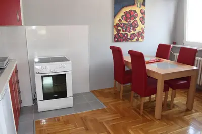 a kitchen with a table and a stove and red chairs at Comfortable apartment near the City Center in Banja Luka