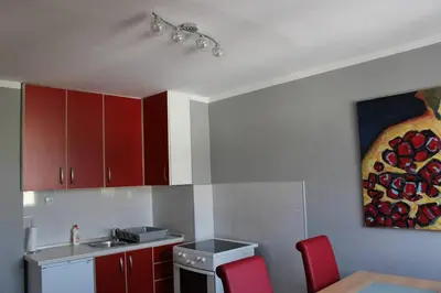 a kitchen with red cabinets and a painting on the wall at Comfortable apartment near the City Center in Banja Luka