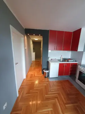 a kitchen with red cabinets and a wooden floor at Comfortable apartment near the City Center in Banja Luka
