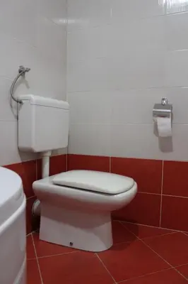 a bathroom with a white toilet and a red floor at Comfortable apartment near the City Center in Banja Luka