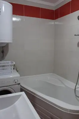 a bathroom with a white tub and a washing machine at Comfortable apartment near the City Center in Banja Luka