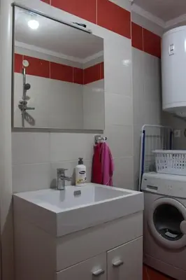 a bathroom with a sink and a washing machine at Comfortable apartment near the City Center in Banja Luka