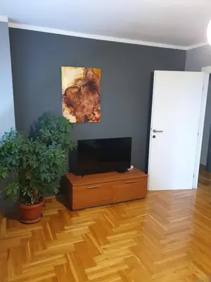 a living room with a flat screen tv and a wooden floor at Comfortable apartment near the City Center in Banja Luka