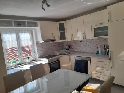 a kitchen with white cabinets and a table with chairs at Apartman Zoran in Livno