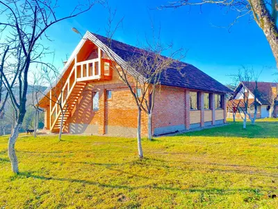a red brick house with a tree in the yard at Vikend na Ozrenu in Bosansko Petrovo Selo