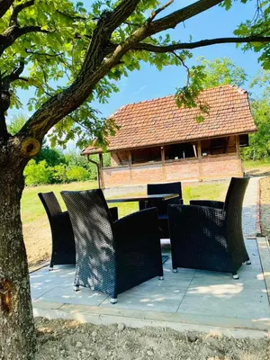 a group of chairs sitting on a patio under a tree at Vikend na Ozrenu in Bosansko Petrovo Selo