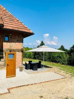 a patio with an umbrella and chairs and a table at Vikend na Ozrenu in Bosansko Petrovo Selo