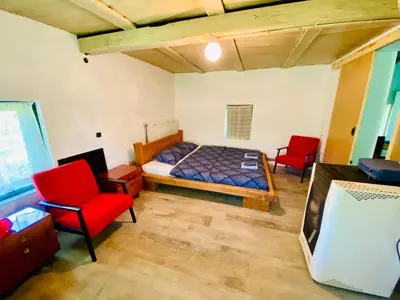 a bedroom with a bed and two red chairs at Vikend na Ozrenu in Bosansko Petrovo Selo