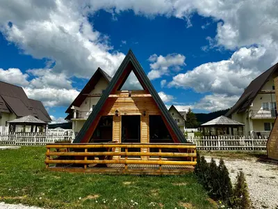 a cabin with a triangular roof in a yard with houses at Vlasic Odmor - Microcastl in Vlasic