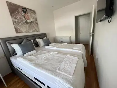 a bedroom with two beds and a painting on the wall at APARTMAN MASA in Banja Luka