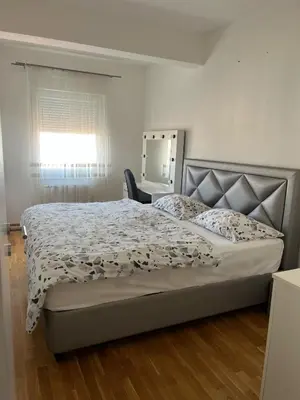 a bedroom with a bed and a window and a chair at APARTMAN MASA in Banja Luka