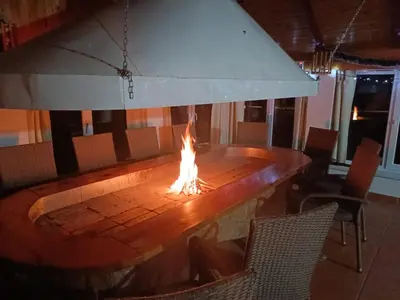 a fire pit in the middle of a room with chairs at Apartman LELI in Kupres