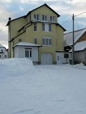 a yellow house with a lot of snow in front of it at Apartman LELI in Kupres