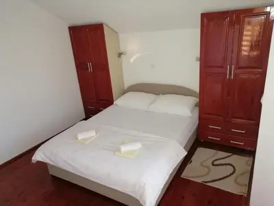 a small bedroom with two beds and wooden cabinets at Apartman LELI in Kupres