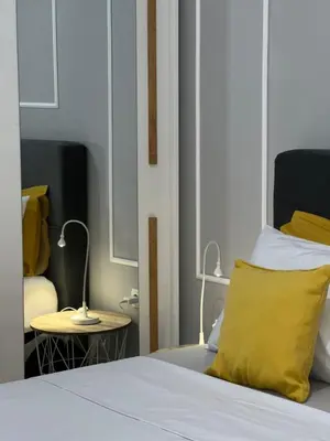 a bed with a yellow pillow and a side table at Apartman Divine in Banja Luka