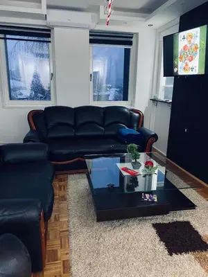 a living room with a black leather couch and a table at Checkmate in Tešanj
