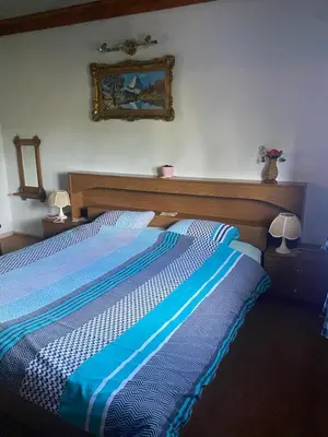 a bed in a bedroom with a blue and white comforter at Farma 2 in Cazin
