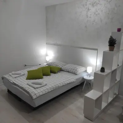 a white bedroom with a bed with green pillows at Apartman Jevrejska Banja Luka in Banja Luka