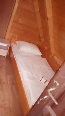 a small bed in a room with wooden floors at Planinske kolibe Šipovo in Šipovo