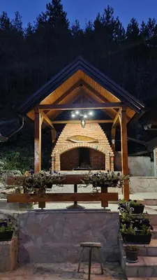 a picnic table in front of a brick fireplace at Planinske kolibe Šipovo in Šipovo